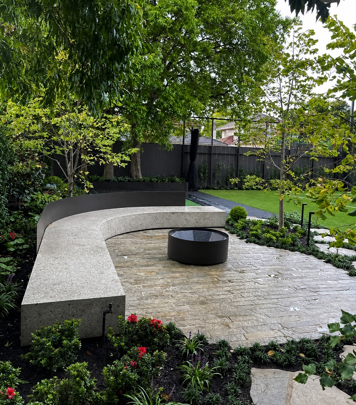 Curved stone bench and paved entertaining area in a landscaped Caulfield garden